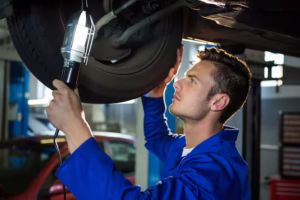 mechanic-examining-car-tyre-using-flashlight